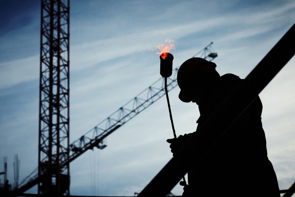 Silhouette of Man Holding Flamethrower at a Construction Site