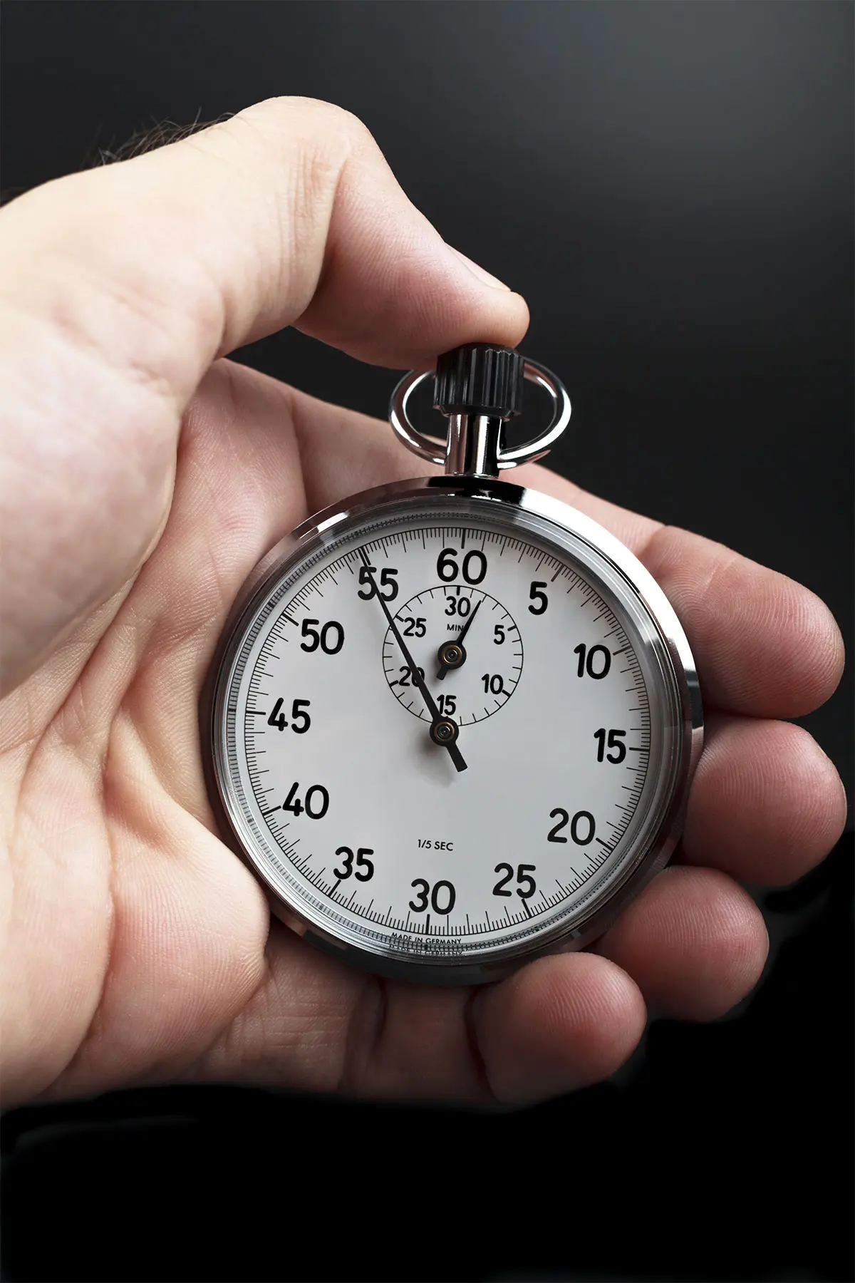 A hand holding a traditional silver stopwatch