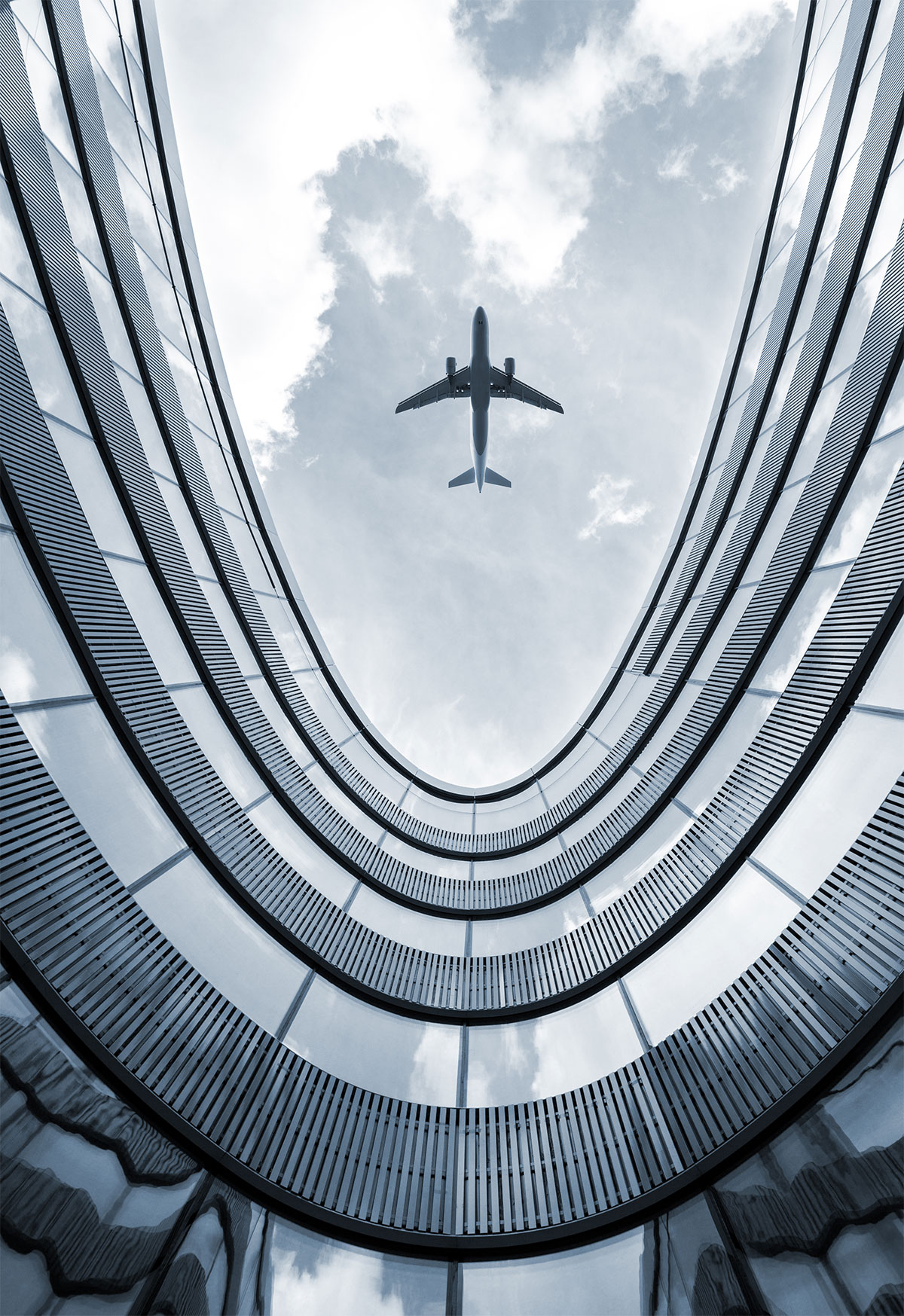A plane flying above a curved modern building