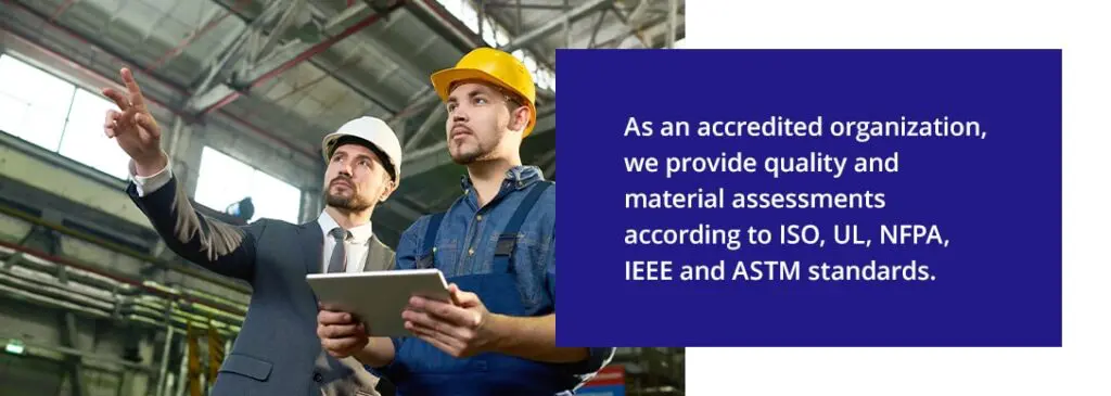 Two engineers wearing safety helmets review site conditions while holding a tablet inside an industrial facility.