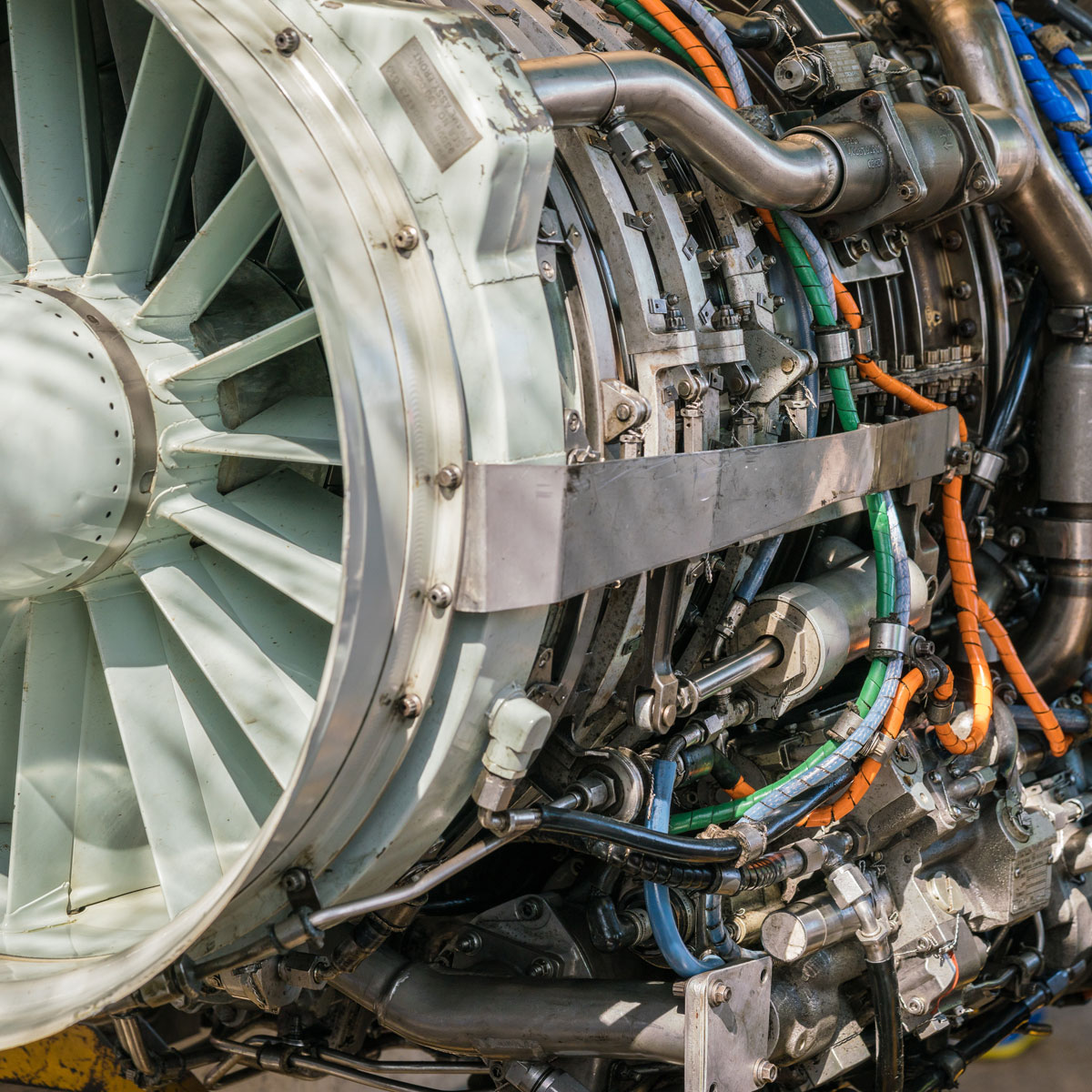 Close-up of an aircraft jet engine during maintenance and inspection, showing turbine components and mechanical systems.